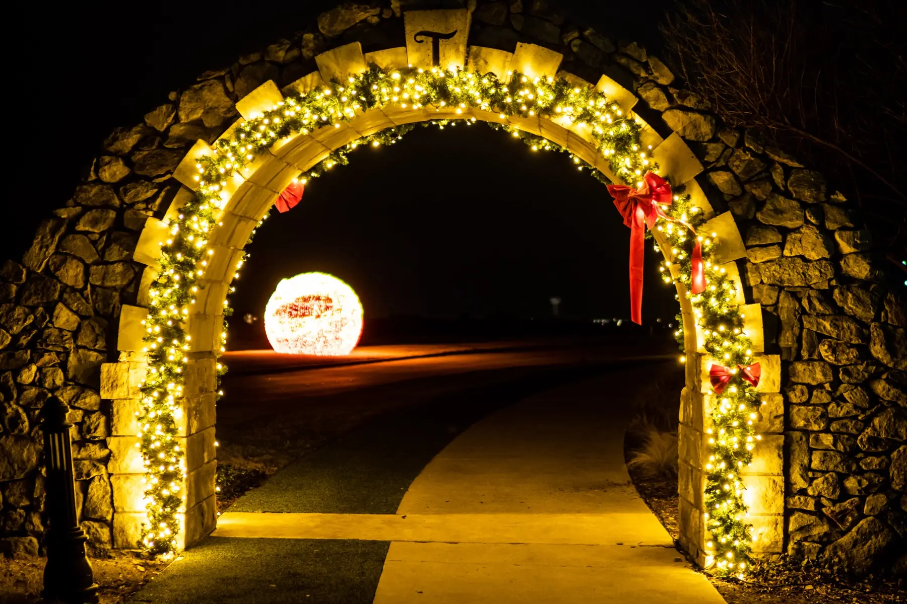 Stone arch wrapped in warm white garland with red bows