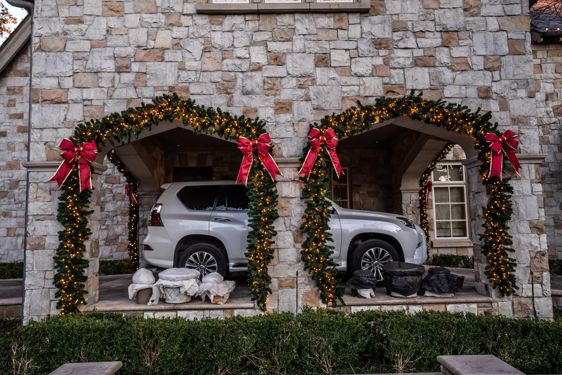 Three stone garage arches wrapped in holiday garland with large red bows